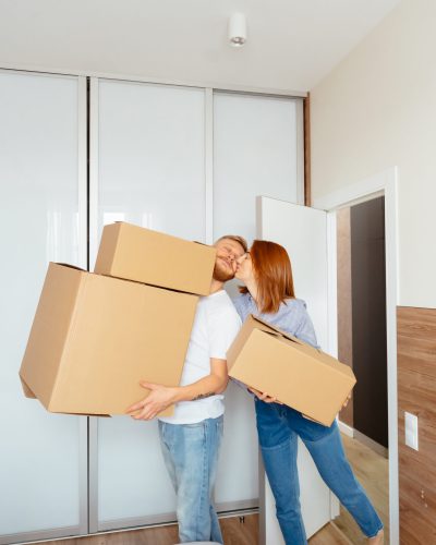 home, people, repair and real estate concept - happy couple holding cardboard boxes and moving to new place